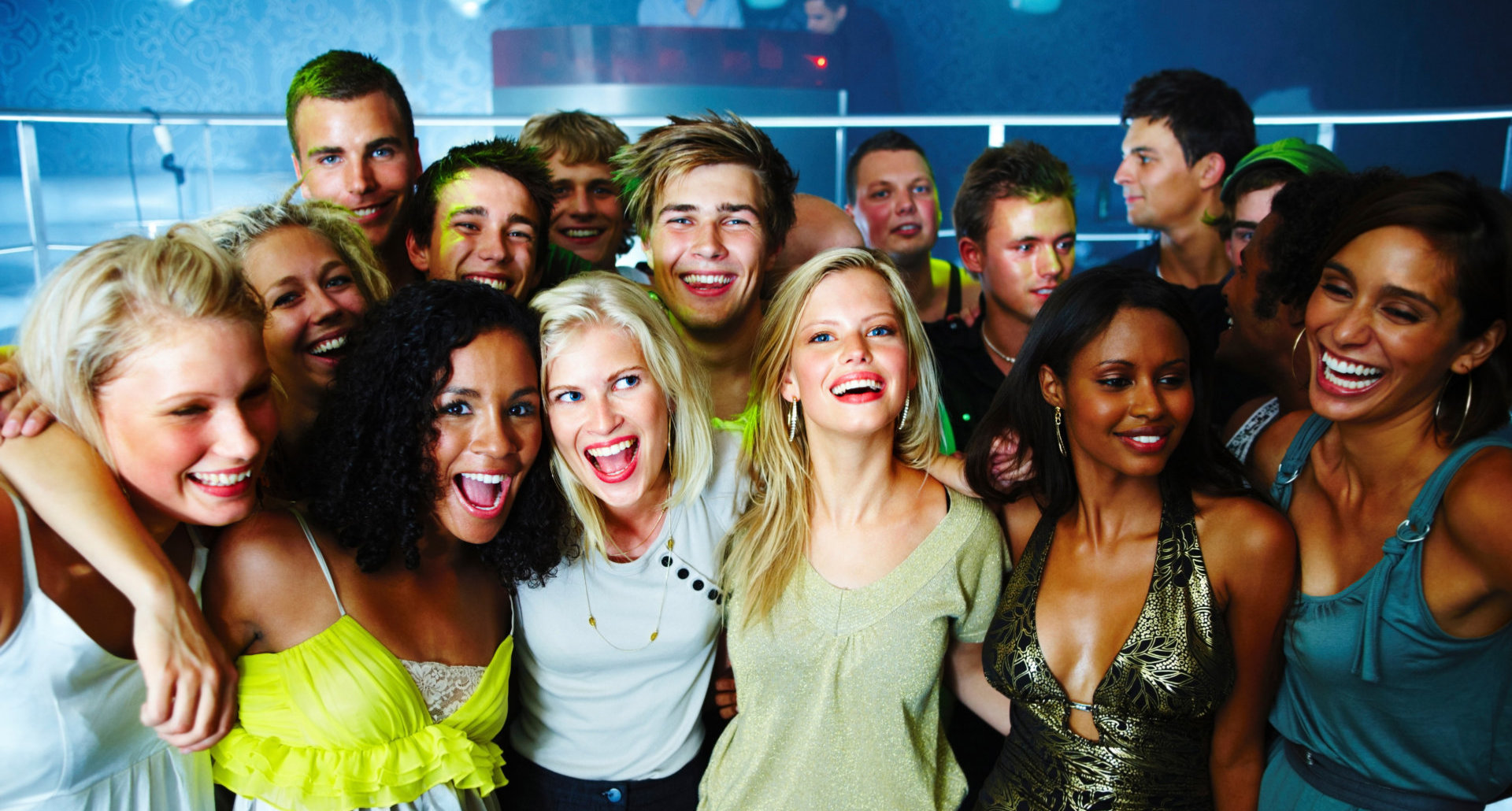 Group of happy young boys and girls standing together in club